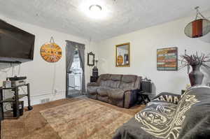 Living room with a textured ceiling and carpet floors