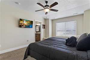 Carpeted bedroom with connected bathroom, ceiling fan, and a textured ceiling