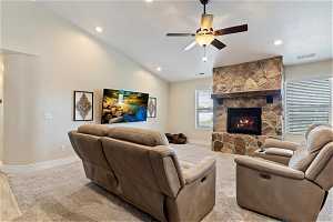 Living room featuring a fireplace, ceiling fan, lofted ceiling, and carpet flooring