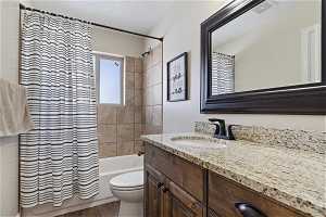 Full bathroom with hardwood / wood-style flooring, shower / tub combo, toilet, and vanity