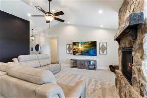 Carpeted living room with a fireplace, ceiling fan, and vaulted ceiling