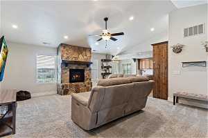 Carpeted living room with vaulted ceiling, ceiling fan, sink, and a fireplace