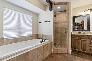 Bathroom featuring shower with separate bathtub and vanity