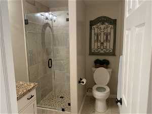 Bathroom featuring tile flooring, vanity, an enclosed shower, and toilet