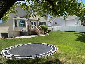 Rear view of property featuring a trampoline and a lawn