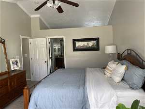 Bedroom with ceiling fan, ensuite bath, carpet flooring, crown molding, and vaulted ceiling