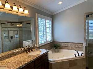 Bathroom featuring ornamental molding, double vanity, and plus walk in shower