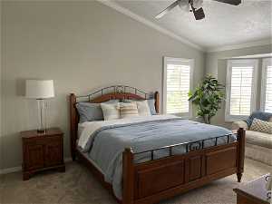 Carpeted bedroom with ornamental molding, vaulted ceiling, ceiling fan, and a textured ceiling