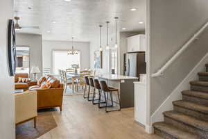 Living room with light hardwood / wood-style flooring, a notable chandelier, and a textured ceiling