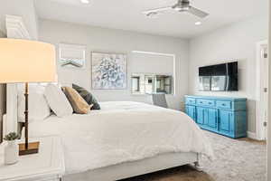 Bedroom with light colored carpet, ceiling fan, and multiple windows