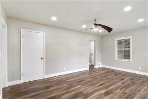 Empty room featuring dark wood-type flooring and ceiling fan