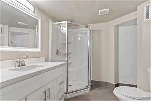 Bathroom with tile floors, vanity, toilet, and a shower with shower door