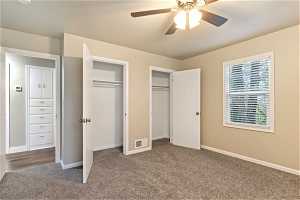 Unfurnished bedroom with dark hardwood / wood-style floors, ceiling fan, and multiple closets