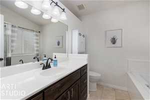 Bathroom featuring oversized vanity, toilet, tile floors, and a bath to relax in