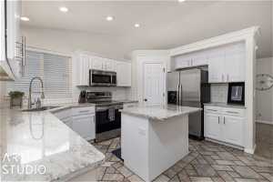 Kitchen with backsplash, stainless steel appliances, a center island, and sink