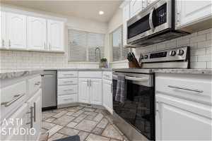 Kitchen featuring white cabinets, tasteful backsplash, and stainless steel appliances