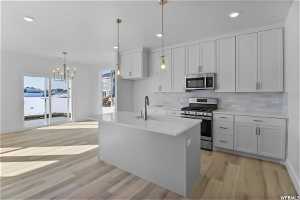 Kitchen featuring sink, appliances with stainless steel finishes, backsplash, and light wood-type flooring
