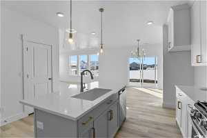 Kitchen featuring sink, light hardwood / wood-style floors, an island with sink, and stainless steel appliances