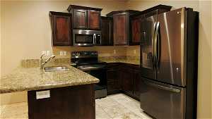 Kitchen featuring sink, kitchen peninsula, light tile floors, and stainless steel appliances
