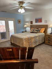 Carpeted bedroom with ceiling fan, french doors, access to outside, and a textured ceiling