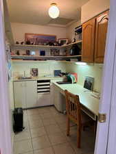 Kitchen with a textured ceiling, built in desk, sink, and light tile flooring