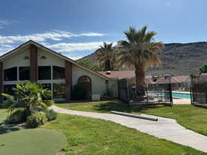 View of front of house featuring a fenced in pool, a mountain view, and a front yard