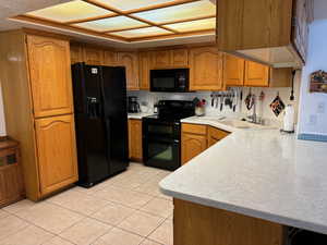 Kitchen featuring sink, light tile floors, and black appliances