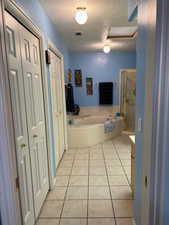 Corridor with light tile floors and a textured ceiling