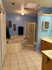 Full bathroom with toilet, a textured ceiling, vanity, separate shower and tub, and tile floors