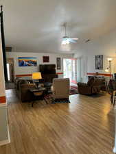 Living room featuring vaulted ceiling, ceiling fan, hardwood / wood-style flooring, and a textured ceiling