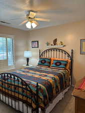 Bedroom featuring a textured ceiling, carpet floors, and ceiling fan