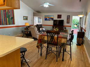 Dining space with lofted ceiling, light hardwood / wood-style floors, and ceiling fan