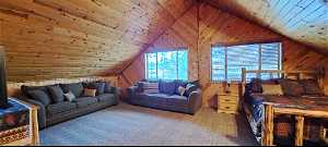 Carpeted bedroom featuring lofted ceiling, wood walls, and wood ceiling