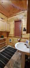 Bathroom featuring wooden ceiling, wood walls, and tile floors