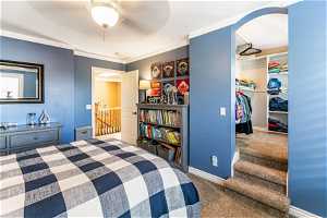 Carpeted bedroom featuring a closet, ceiling fan, and crown molding