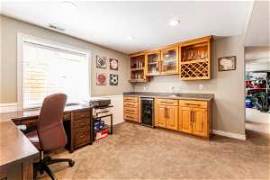 Office area with light carpet, sink, and beverage cooler