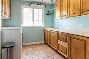 Washroom with cabinets, a healthy amount of sunlight, light tile floors, and washer / dryer
