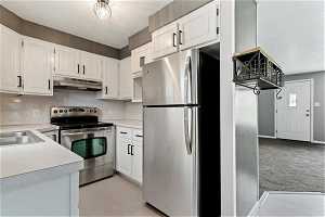 Kitchen with new LVP flooring, sink, white cabinets, and stainless steel appliances