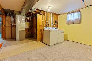 Basement featuring carpet floors, electric water heater, and washer and clothes dryer