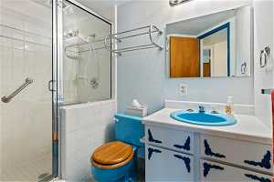 Bathroom featuring vanity with extensive cabinet space, a shower with shower door, and toilet