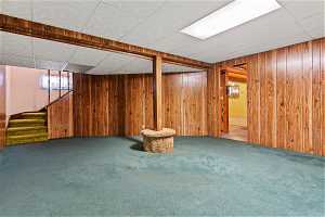 Basement with wood walls, a paneled ceiling, and carpet floors