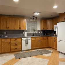 Kitchen featuring light hardwood / wood-style floors, white appliances, backsplash, and sink