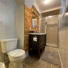 Bathroom with a shower with door, tile floors, vanity, and toilet