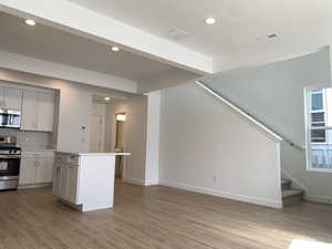 Kitchen featuring a center island, stainless steel appliances, white cabinetry, and light wood-style floors