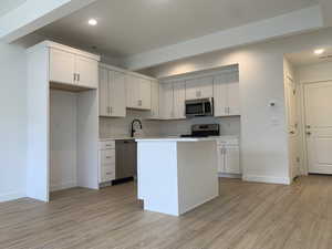 Kitchen featuring appliances with stainless steel finishes, white cabinets, and light wood-style floors