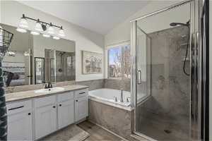 Primary Bathroom with independent shower and bath, vanity, hardwood / wood-style floors, and vaulted ceiling