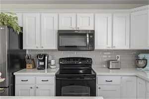 Kitchen featuring white cabinets, stainless steel appliances, and backsplash