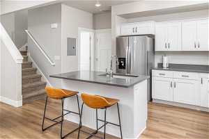 Kitchen with a kitchen island with sink, sink, light hardwood / wood-style floors, and stainless steel fridge