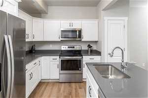 Kitchen featuring white cabinets, sink, light wood-type flooring, and stainless steel appliances