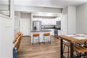 Kitchen featuring white cabinets, sink, stainless steel appliances, and light wood-type flooring